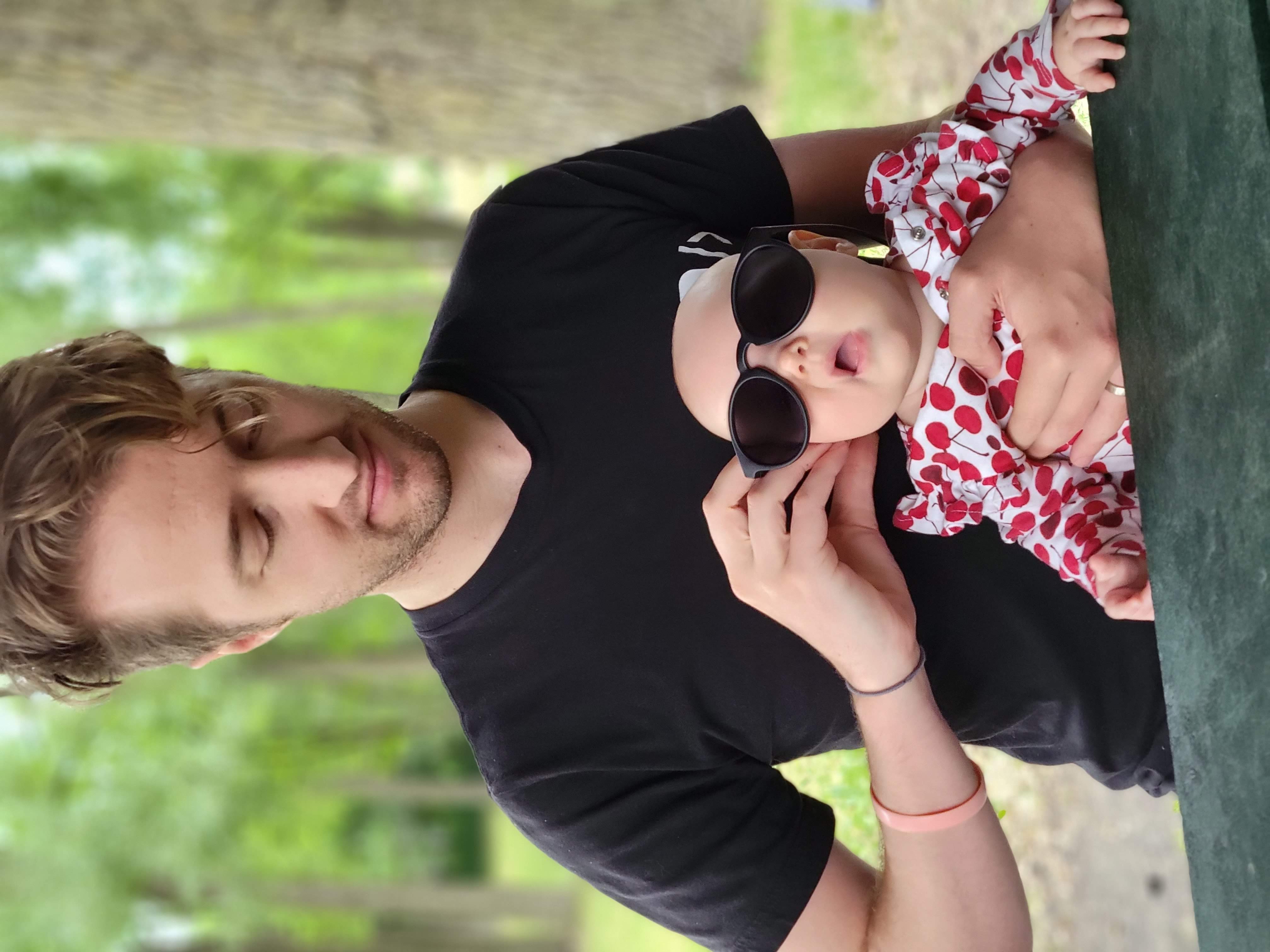 baby wearing sunglasses, sitting in father's lap